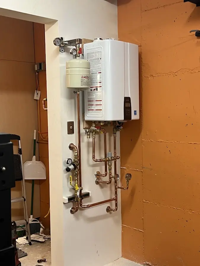 Plumbing technician inspecting water heater connections in Van Buren